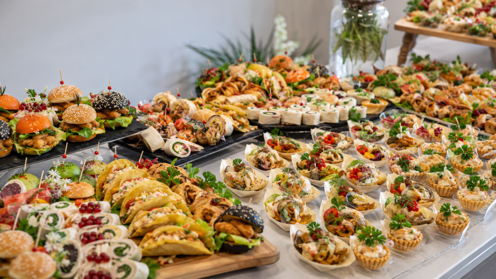Różnorodny bufet przekąsek z mini burgerami, tortillami, tacos i tartaletkami na przyjęcie